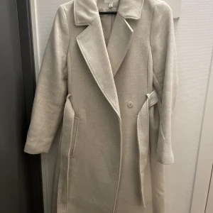 Beige kappa - Beige kappa från h&m, köpt förra året men har knappt använt den 3 gånger. Är i helt nytt skick!