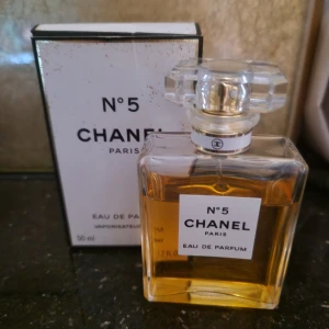 Chanel No. 5 Eau de Parfum - Säljer en klassisk Chanel No. 5 Eau de Parfum, 50 ml. Flaskan är elegant och fyrkantig med en stilren etikett och en lyxig, genomskinlig kork. Perfekt för den som älskar tidlös elegans och en sofistikerad doft. Kommer med originalförpackning.