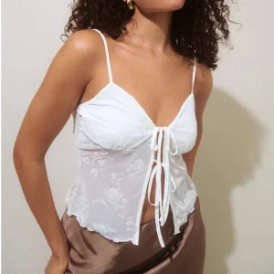 Söt topp med knytsnöre - Jättesöt topp som är perfekt till fester eller till sommaren🌸Köpt på Gina Tricot för 300kr i butik så kunde ej returnera, toppen är aldrig använd! Den är ganska genomskinlig förrutom vid bysten där det är dubbelt tyg.