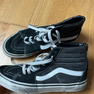 Svarta sneakers från Vans - Säljer ett par klassiska svarta Vans sneakers i bra skick. De har en vit sula och den ikoniska vita sidoremsan. Skorna har snörning och är perfekta för vardagsbruk. Sulan har det typiska rutmönstret för bra grepp.