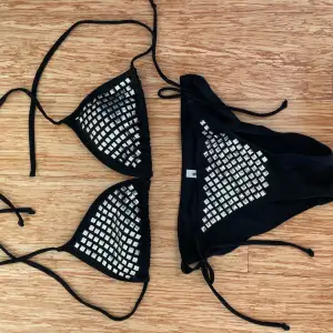 Snygg svart bikini från Gina Tricot i storlek S. Den har coola silverdetaljer som ger en glittrig look. Bikinin har knytband för justerbar passform och är perfekt för sommarens stranddagar. Materialet känns bekvämt och stilrent. Perfekt för dig som vill sticka ut lite extra! ✨