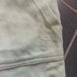 Ljusa juicy mjukisbyxor med snörning - Säljer ett par ljusa juicybyxor i mycket bra skick. De har en bekväm passform med snörning i midjan och praktiska fickor både fram och bak. Perfekta för en avslappnad dag hemma eller en snabb tur till affären. Broderad logga på ena benet ger en extra touch.