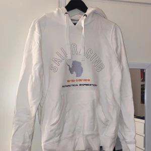 Vit hoodie från Sail Racing - Säljer en vit hoodie från Sail Racing med tryck av Antarktis och texten 'Antarctica Expedition'. Hoodien har en känguruficka och justerbar huva med snören. Perfekt när det är lite kallare ute🤗❄️ 