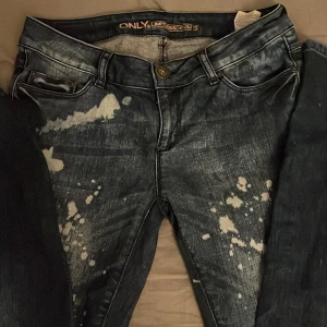 Mörkblå jeans med stänkmönster från Only - Snygga mörkblå jeans från Only med unikt stänkmönster. De har en klassisk femficksdesign och knappgylf. Perfekta för en cool och avslappnad stil.
