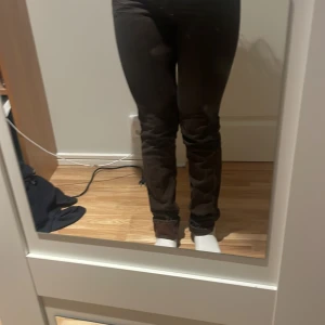 Bruna jeans från Acne - Snygga bruna jeans från Acne med klassisk design och knappdetaljer. Perfekta för en stilren look. De har en dragkedja och är tillverkade i ett robust material.