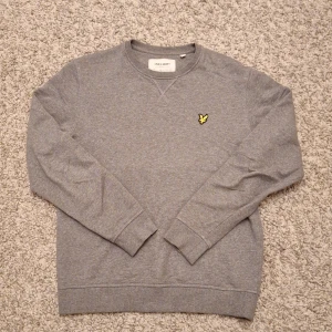 Grå sweatshirt från Lyle & Scott - Säljer en stilren grå sweatshirt från Lyle & Scott då den inte kommer till användning längre. Den har en Regular fit med rund hals och passar superbra för både en mer stilig outfit samtidigt som en mer avslappnad outfit. Den har använts några gånger och har inga defekter. Modellen är ca 180 cm lång. Skick: 8/10