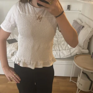 Vit topp från Gina Tricot - Säljer en söt vit topp från Gina Tricot med korta ärmar och volangdetalj vid nederkanten. Storlek 158/164! Vi kan diskutera pris!💓