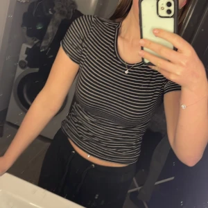 Svart och vit randig t-shirt  - Säljer en svart och vit randig t-shirt från H&M. Den har en klassisk rund hals och korta ärmar, perfekt för en avslappnad stil. T-shirten är gjord i ett mjukt och bekvämt material. Väldigt fin tröja!🖤🤍🥂