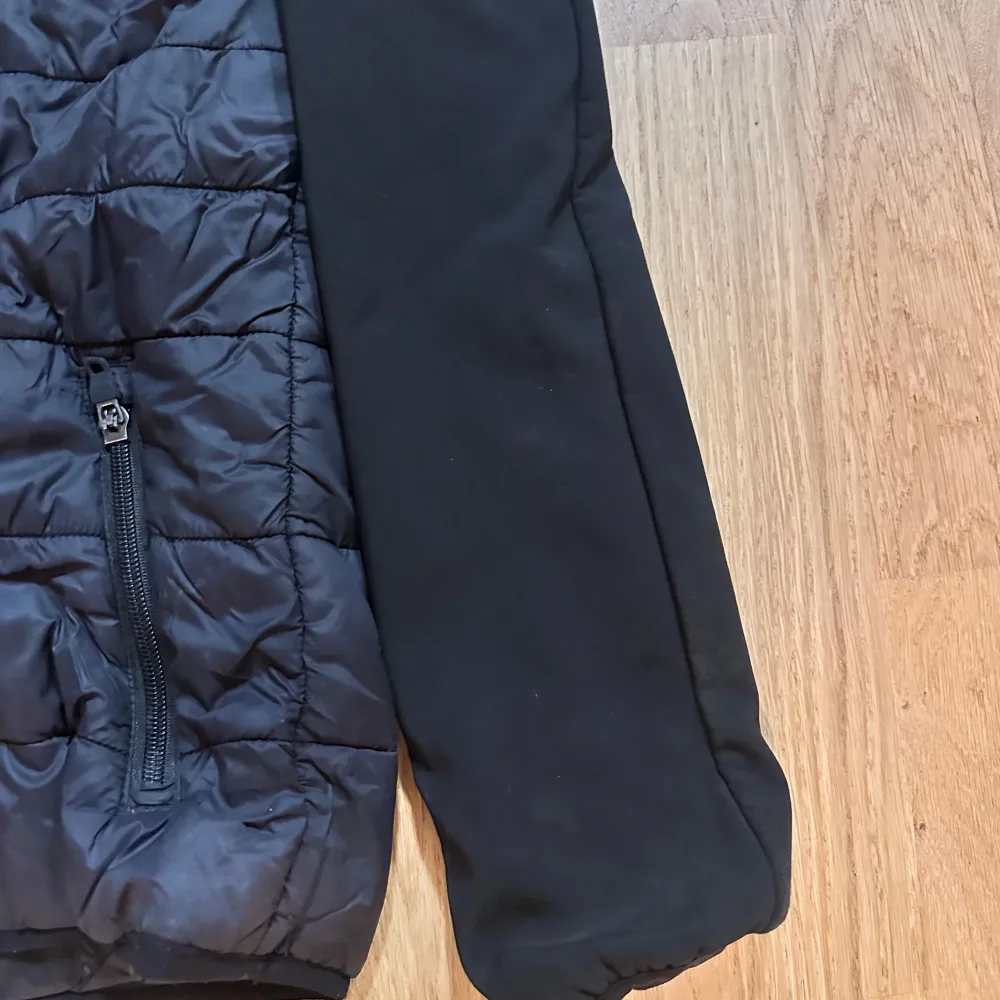 Säljer en svart pufferjacka från Nike med huva och dragkedja framtill. Jackan har långa ärmar och två praktiska fickor med dragkedja. Perfekt för kyligare dagar.. Takit.