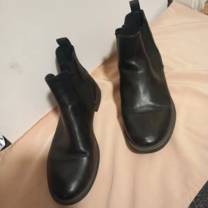 Svarta boots från Alley - Snygga svarta boots från Alley i skinn. De har en klassisk design med elastiska paneler på sidorna för enkel på- och avtagning. Perfekta för en stilren look.