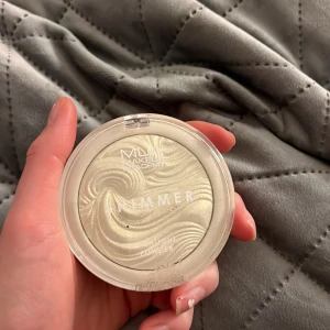 Shimmer Highlighter från MUA Makeup Academy - Snygg highlighter med skimrande finish från MUA Makeup Academy. Den har en vacker, vågig design i en ljus nyans som ger en strålande lyster. Perfekt för att framhäva kindben och andra ansiktsdrag.