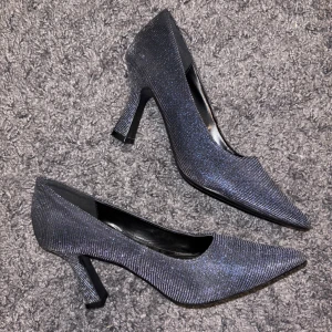Glittriga klackar med spetsig tå - Snygga glittriga klackar i glittrigt blått med spetsig tå och klack. Perfekta för att ge en extra touch till din outfit. De har en elegant design som passar till många tillfällen. Storleken är 36 men passar mig som har 37-38. Bara använda 3 gångermed extrainlägg innuti för bekvämlighet 💕 priset är diskuterbart 💕💕💕