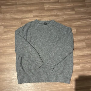 Grå stickad tröja från H&M - Säljer en grå stickad tröja från H&M i relaxed fit. Tröjan har långa ärmar och ribbade muddar vid ärmslut och nederkant. Perfekt för kyligare dagar!