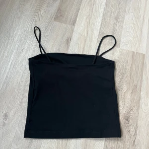 Svart linnetopp från Gina Tricot - Säljer en stilren svart linnetopp från Gina Tricot. Toppen har smala axelband och en enkel design som passar perfekt till olika outfits. Perfekt för varma dagar eller som ett lager under andra plagg.