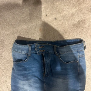 Blå jeanskjol - Säljer en klassisk blå jeanskjol med en bekväm passform. Kjolen har en traditionell femficksdesign och bälteshällor. Perfekt för en avslappnad stil.