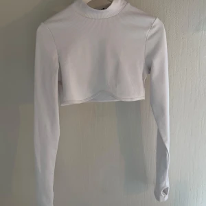 Tröja - Säljer en stilren vit ribbad croppad tröja från H&M  med långa ärmar. Perfekt för en trendig look. Passar bra till både jeans och kjol.