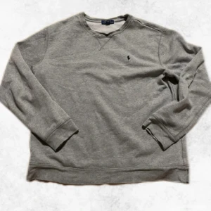 Grå sweatshirt från Polo Ralph Lauren - Säljer en snygg grå sweatshirt från Polo Ralph Lauren. Den har en ganska bred passform och en något utsliten krage men förutom kragen är den i fint skick. Den är i storlek 18 till 20 barn storlek men sitter som en S. Vid några frågor eller funderingar är det bara att höra av sig