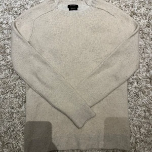 Beige stickad tröja från Massimo Dutti - Säljer en stilren beige stickad tröja från Massimo Dutti. Tröjan har långa ärmar och ribbade muddar vid ärmslut och nederkant. Perfekt för kyligare dagar.