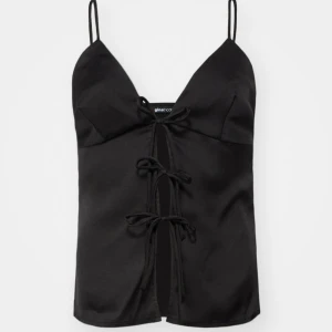 Svart satinlinne från Gina Tricot - Elegant svart satinlinne från Gina Tricot med smala axelband och knytning framtill. Perfekt för en stilren look. Lappen sitter kvar o h är alltså aldrig använd 