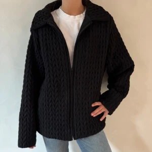 Svart stickad jacka - Säljer en svart stickad jacka med dragkedja framtill. Jackan har en normal passform och långa ärmar, perfekt för kyligare dagar. Den har en snygg och enkel design som passar till det mesta.