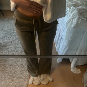 Gröna mjukisbyxor från Juicy Couture - Säljer ett par militärgröna lågmidjade mjukisbyxor från Juicy Couture. Byxorna är näst intill nyskick (använda 1-2 gånger) och de är inköpta för 1200kr. De är i storlek XS och jag är 174 cm lång och de passar mig bra i längden. Priset är diskuterbart🫶💕