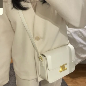 Vit axelväska med gulddetaljer - Elegant vit axelväska med en stilren design och guldfärgad spänne. Väskan har en praktisk dragkedja inuti för extra säkerhet och organisation. Perfekt för att ge en touch av lyx till din outfit. Pris kan diskuteras