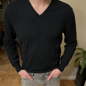 Massimo Dutti tröja  - Säljer en elegant svart v-ringad tröja från Massimo Dutti. Tröjan är tillverkad i en lyxig blandning av bomull, silke och kashmir, vilket ger en mjuk och bekväm känsla. Perfekt för en stilren look.