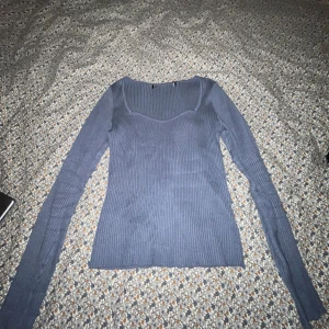 Blå ribbad tröja - Säljer en stilren blå ribbad tröja med långärmad design. Tröjan har en v-ringad hals och är perfekt för en avslappnad look. Passar bra till både jeans och kjol.