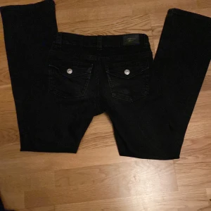 Svarta jeans från Gina Tricot - Snygga svarta jeans från Gina Tricot med klassisk femficksdesign och knappgylf. Perfekta för en stilren look och passar till många olika outfits.