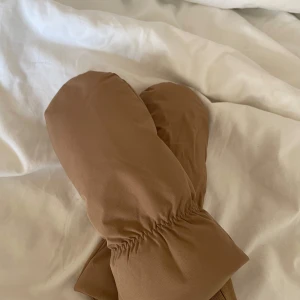 Bruna tumvantar  - Säljer ett par bruna puffer tumvantar från Cubus. De har en ribbad mudd och är perfekta för att hålla händerna varma under kalla dagar. Vantarna är i storlek S-M och har en stilren design.