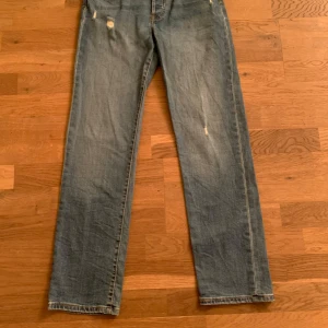 Levis 501 jeans - Klassiska Levis 501 jeans i blå denim med slitna detaljer. De har en rak passform och knappgylf. Perfekta för en avslappnad stil.