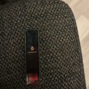 Läppstift Lip Power i nyansen Tiphaine - Säljer ett elegant läppstift från Lip Power i nyansen Tiphaine. Förpackningen är stilren och svart med en genomskinlig del som visar den vackra röda färgen. Perfekt för en kraftfull och glamorös look!
