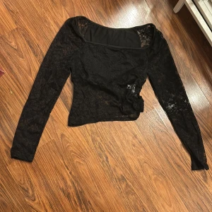 Svart spetsblus från Shein - Säljer en elegant svart spetsblus från Shein i storlek XS. Blusen har långa ärmar och en vacker blommig spetsdesign. Perfekt för festliga tillfällen eller en utekväll. Den är i nyskick och redo att bäras av någon som älskar stil och elegans. 🌟