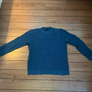 Blå stickad tröja från Riley - Säljer en snygg blå stickad tröja från Riley. Perfekt för kyliga dagar med sin mjuka och bekväma passform. Tröjan har långa ärmar och en klassisk rund halsringning. Passar både till vardags och lite finare tillfällen. 🧶💙