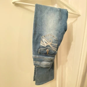 Blå jeans med broderad ficka - Snygga blå jeans med en cool broderad detalj på bakfickan. Perfekta för en avslappnad stil, de har en klassisk look med en modern twist. Passar bra till både vardag och fest!