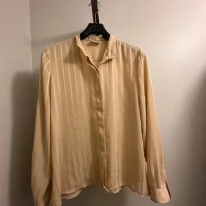 Beige randig blus - Beige blus med diskreta ränder. Helt oanvänd från Oscar of Sweden i storlek 44!