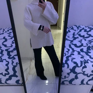 Vit stickad polotröja - Säljer en supermysig vit stickad polotröja med långa ärmar och en avslappnad passform. Perfekt för kyliga dagar och att mysa i hemma. Tröjan har en slits på sidorna som ger en extra touch av stil. Passar perfekt till jeans eller leggings!