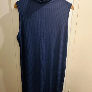 Mörkblå ärmlös klänning från Bodyflirt - Snygg mörkblå ärmlös klänning från Bodyflirt i storlek L. Klänningen har en ribbad struktur som ger en stilren look. Perfekt för både vardag och festliga tillfällen. Den är bekväm och lätt att matcha med olika accessoarer.