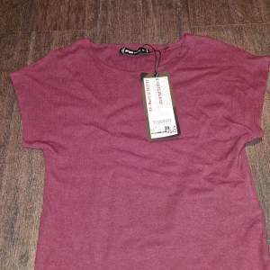 Vinröd t-shirt  - Säljer en snygg vinröd t-shirt från New yorkers i storlek M. Den är helt ny med lapp kvar och har en enkel, stilren design. Perfekt för vardagsbruk eller att matcha med en cool jacka. Materialet känns mjukt och skönt mot huden.