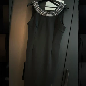 Klänning  - Säljer min fantastiska svarta klänning som har ett elegant kristallmönster upptill. Den har bara använts två gånger, så den är i toppskick!