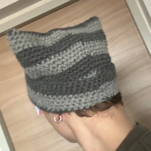 Stickad cat beanie mössa - Cool stickad katt mössa! Använt tre gånger, så ganska oanvänd. Passar 55-60 cm runt huvudet. Mössan är i fint skick.