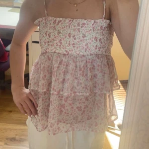 Söt topp - Söt topp från Gina Young med blommor på🩷man kan ta av banden och göra den till en bandeutopp eller kjol. Den är i storlek 170 men passar mig som brukar ha xs-s