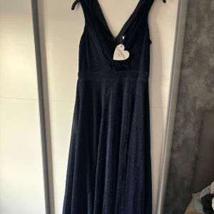 Balklänning mörkblå - Balklänningen är mörkblå med glitter i och är helt oanvänd med ettiken fortfarande kvar, den är köpt på bubbleroom och är i storlek L