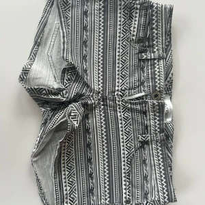Mönstrade shorts i svart och vitt - Säljer ett par snygga, lågmidjade shorts med svartvitt mönster. De har en cool, geometrisk design med dragkedja och knapp framtill. 