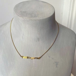 Guldhalsband med text - Säljer ett stilrent guldhalsband med texten 'tvillingarna'. Halsbandet har en tunn kedja och en elegant design som passar perfekt för både vardag och fest. Det är i bra och har en enkel låsning baktill.