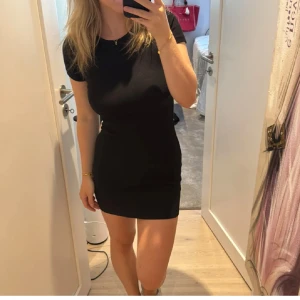 Svart kortklänning med öppen rygg - Säljer en superfin svart kortklänning med en snygg öppen rygg. Perfekt för fest eller en utekväll! Klänningen är tight och har korta ärmar. Den är i nyskick och redo för att bäras av någon som vill sticka ut.
