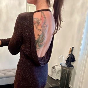 Klänning - Läcker glittrig klänning. Svart klänning med gott om glansig tråd i, typ åt kopparfärgade hållet. Djup ringning i ryggen. Säljes pga aldrig tillfälle att använda den. Hittills använd 1-2 ggr endast.