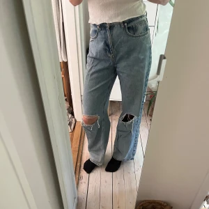 Jeans från na-kd  - Vida jeans med hål på knäna. Midjemått: 34 cm rakt över. Innerbenslängd: 80 cm. 