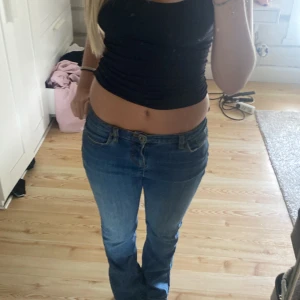 Blå jeans med blommigt broderi - Säljer ett par snygga blå jeans med blommigt broderi på bakfickan. De är lågmidjade och har en straight passform som ger en avslappnad look. Perfekta för både vardag och fest!