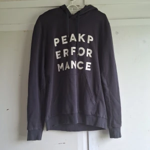 Svart hoodie från Peak Performance - Säljer en svart hoodie från Peak Performance i storlek M. Den är superbekväm och perfekt för höst och vinter. Hoodien har en stor ficka på magen och texten 'Peak Performance' tryckt i vitt på framsidan. Den har långa ärmar och en justerbar huva med snören. 